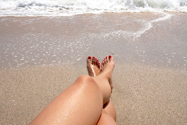 Ginocchia e piedi femminili al mare