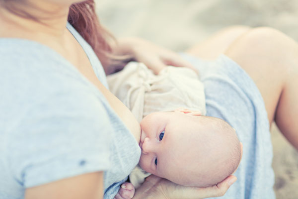 Mamma che allatta in spiaggia