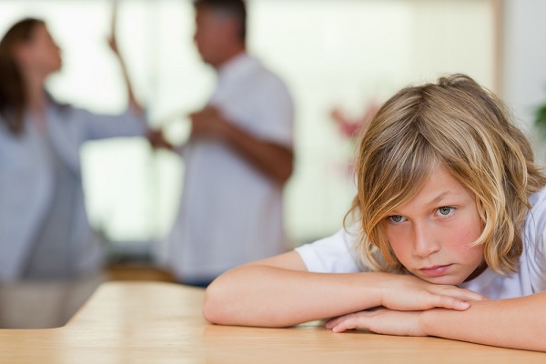 Worried looking boy with fighting parents behind him