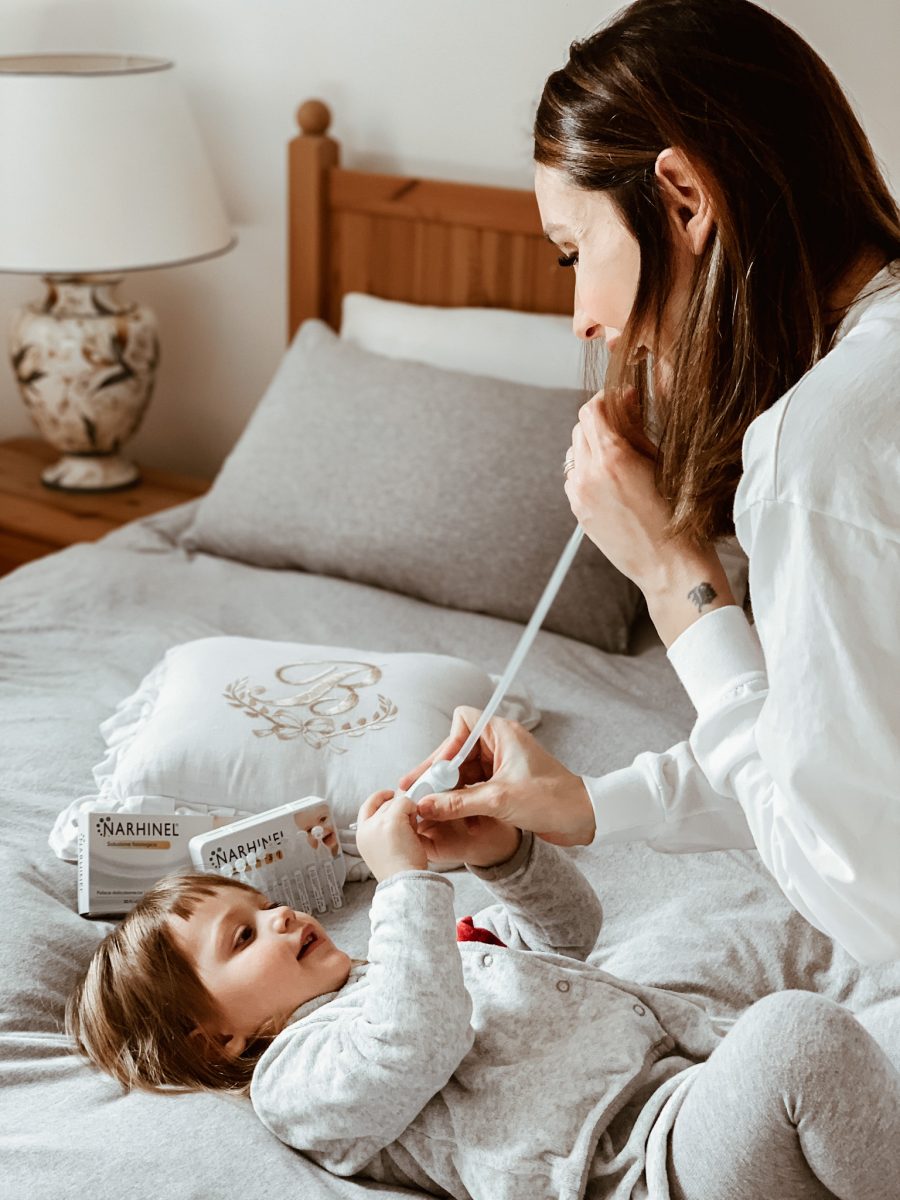 mamma che usa l'aspiratore nasale per pulire il naso dei bambini