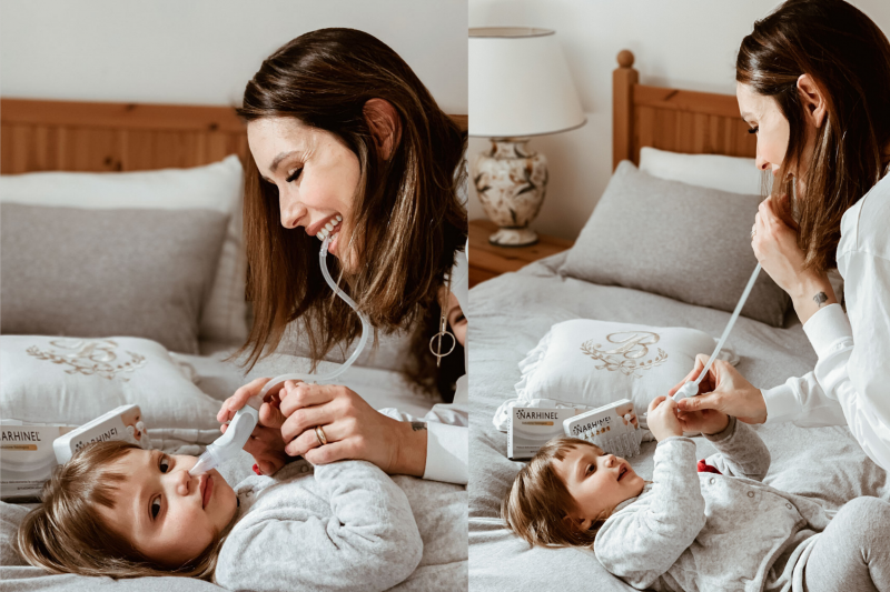mamma che usa l'aspiratore nasale per pulire il naso dei bambini